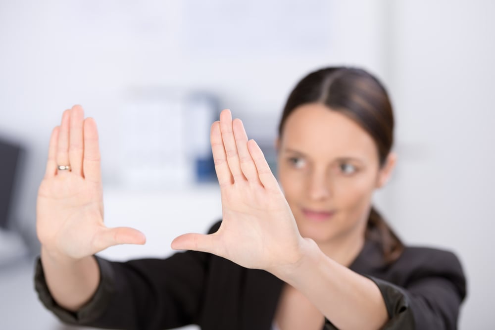 Mid adult businesswoman making hand frame in office, focus hands Mid adult businesswoman making hand frame in office, focus hands